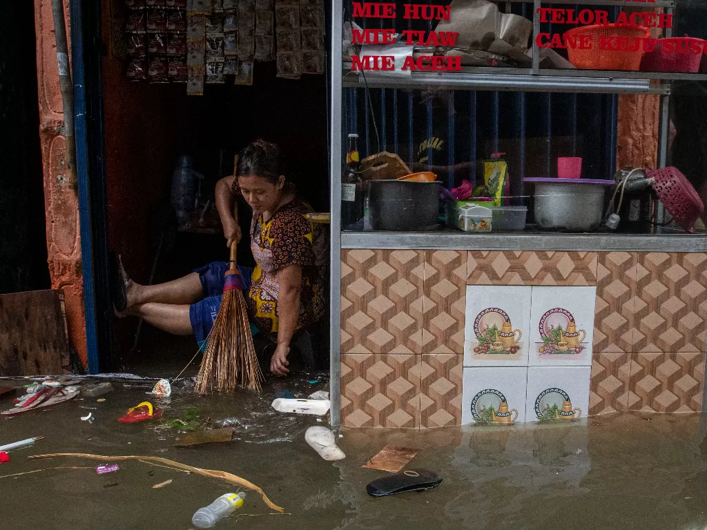 Warga membersihkan warungnya yang terendam rob atau banjir pasang air laut di Ancol. (ANTARA FOTO/Aditya Pradana Putra/rwa)