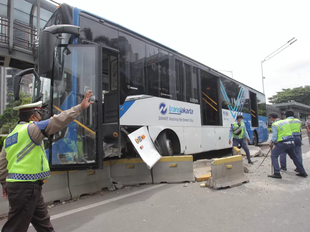 Petugas berupaya mengevakuasi bus TransJakarta yang menabrak separator di Jalan Jenderal Sudirman, Jakarta, Jumat (3/12/2021). (ANTARA FOTO/Reno Esnir/tom)