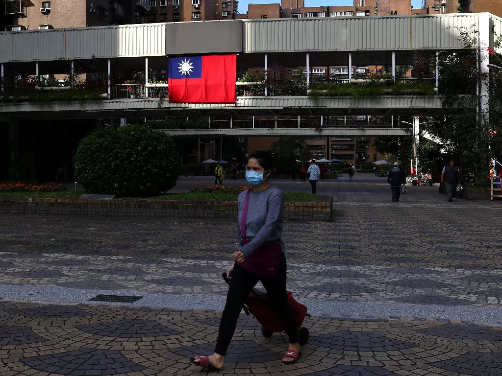 Seorang wanita berjalan melewati bendera Taiwan. (REUTERS/Ann Wang)