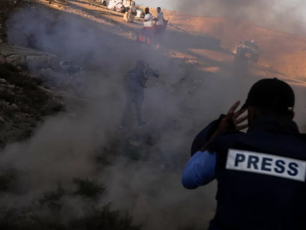 Paramedis dan jurnalis selama bentrokan antara pasukan Israel dan demonstran Palestina yang memprotes permukiman Israel, di Tepi Barat 27 Juli 2021. (REUTERS / Raneen Sawafta)