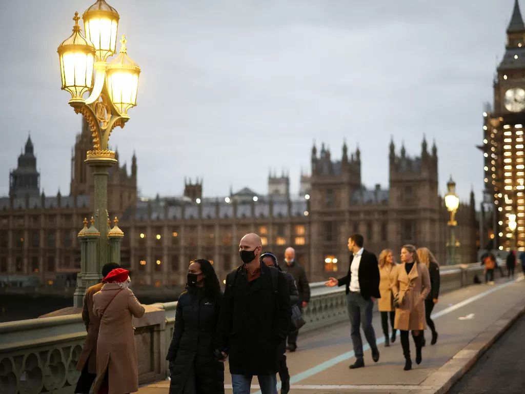 Orang-orang berjalan melintasi Jembatan Westminster, di tengah wabah penyakit virus corona (COVID-19) di London, Inggris. (REUTERS/HENRY NICHOLLS)