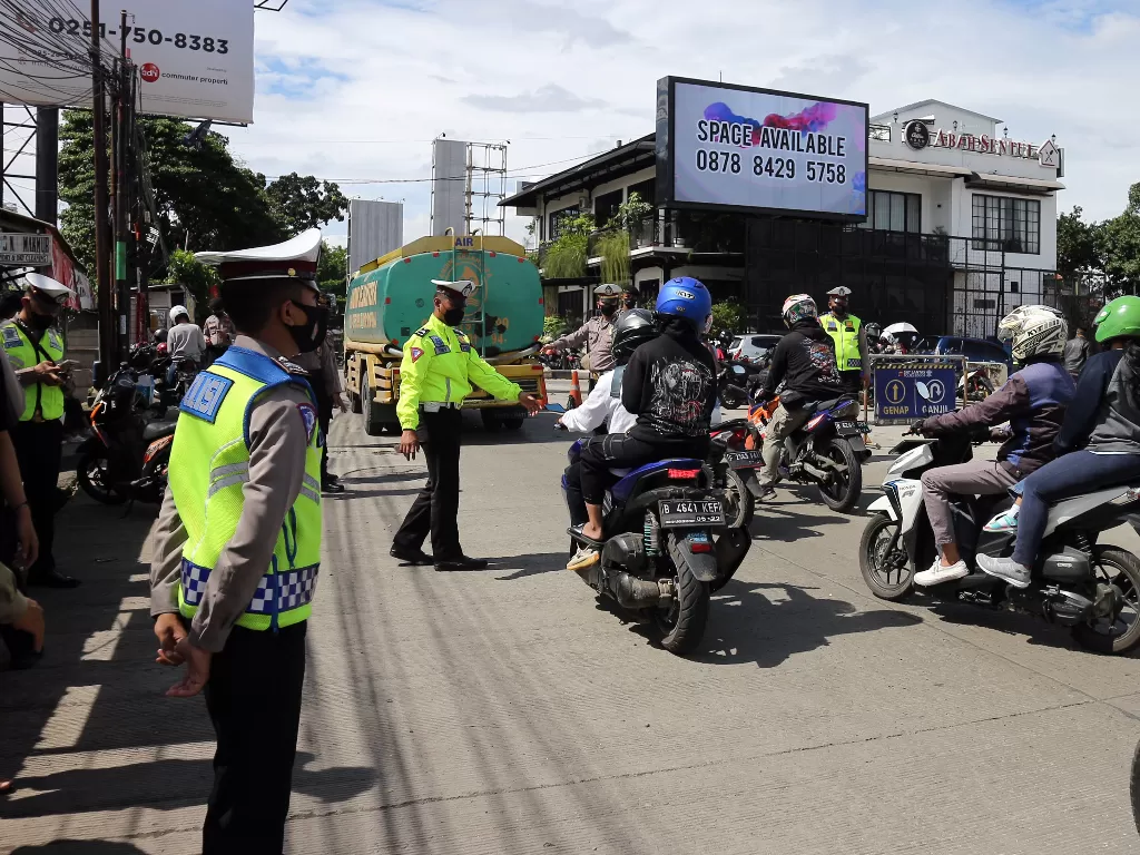 Polisi menghentikan pengendara sepeda motor dengan plat nomor ganjil. (Foto: ANTARA/Yulius Satria Wijaya)