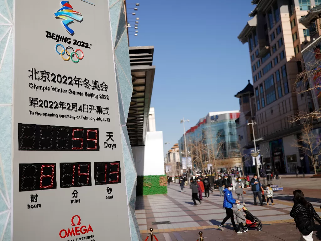 Pejalan kaki berjalan melewati jam hitung mundur Olimpiade Musim Dingin Beijing 2022 di Beijing, China, 7 Desember 2021. (REUTERS/Carlos Garcia Rawlins)