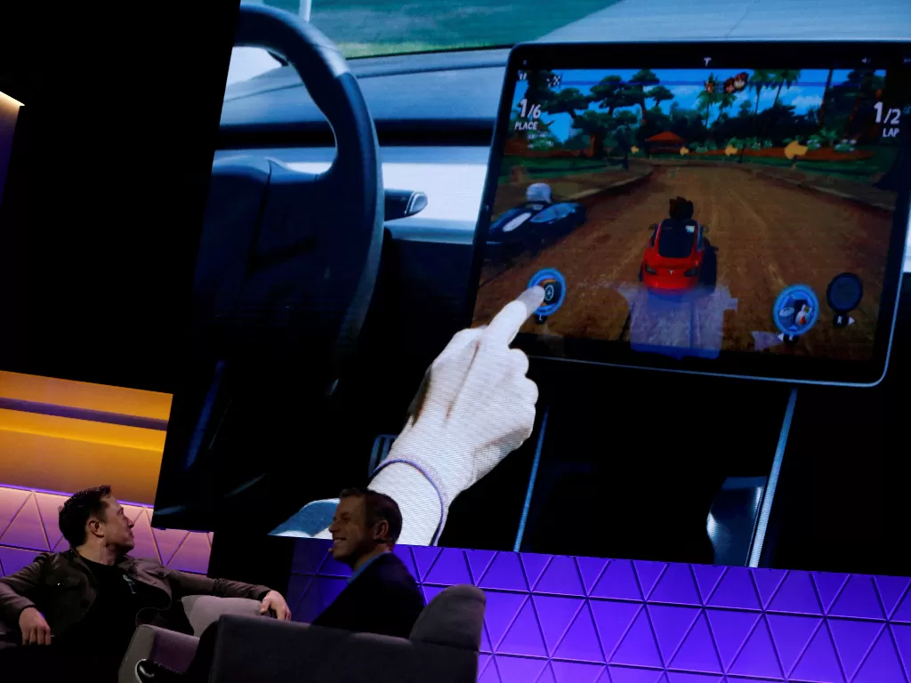 Elon Musk saat menonton dasbor mobil Tesla yang digunakan untuk bermain game. (photo/REUTERS/MIKE BLAKE)