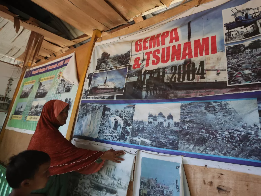 Warga melihat gambar-gambar kerusakan akibat bencana gempa dan gelombang tsunami 26 Desember 2004 yang berada di kawasan kubah masjid terdampar di Desa Gurah, Aceh Besar, Aceh. (Foto: ANTARA/Irwansyah Putra)