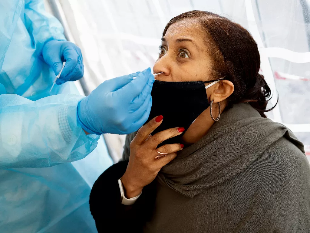 Seorang wanita menjalani tes penyakit virus corona (COVID-19) di apotek saat infeksi COVID-19 meningkat, di Roma, Italia. (REUTERS/GUGLIELMO MANGIAPANE)