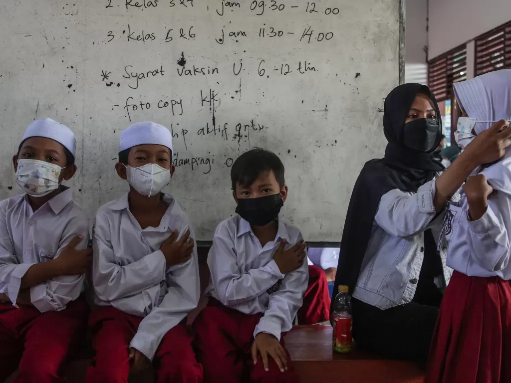 Sejumlah siswa menunggu surat vaksin usai disuntik vaksin Sinovac saat giat vaksinasi Covid-19 massal bagi anak usia 6-11 tahun di SD Nurul Ihsan, Palangkaraya, Kalimantan Tengah, Senin (27/12/2021). (ANTARA FOTO/Makna Zaezar)