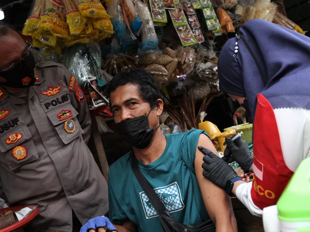 Tim medis Polresta Kendari melakukan vaksinasi COVID-19 dengan mendatangi pedagang di lapak jualannya di Pasar Baruga, Kendari, Sulawesi Tenggara, Selasa (4/1/2022). (ANTARA/Jojon)