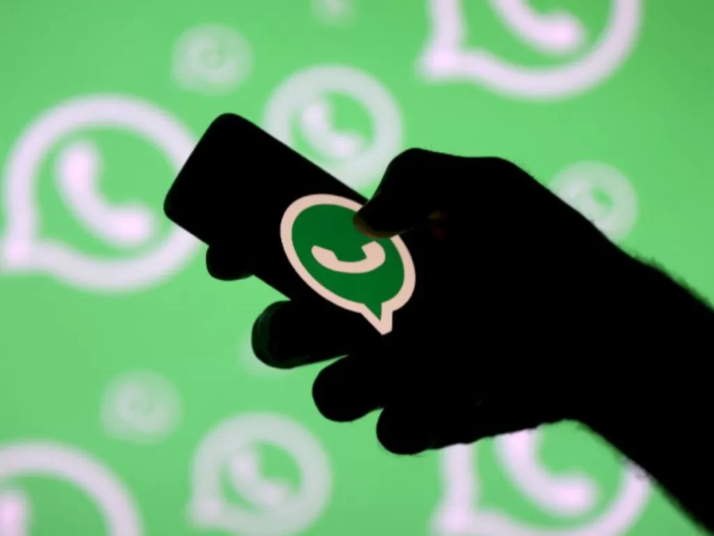 lustrasi seseorang sedang memegang smartphone dengan logo WhatsApp (REUTERS/Dado Ruvic)