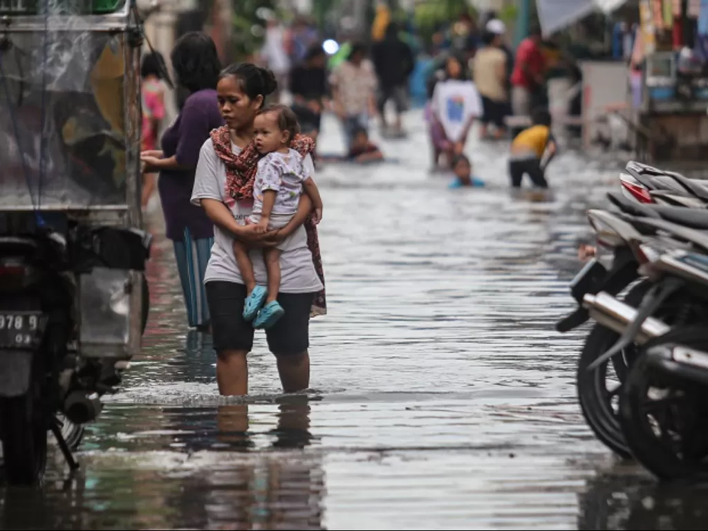 Seorang warga berjalan di tengah banjir di kawasan Cengkareng, Jakarta. (ANTARA FOTO/Fauzan)