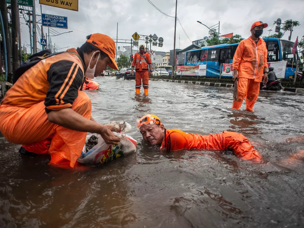 Petugas PPSU membersihkan sampah yang menyumbat saluran air saat banjir di Jalan Gunung Sahari, Mangga Dua, Jakarta. (ANTARA Aprillio Akbar)