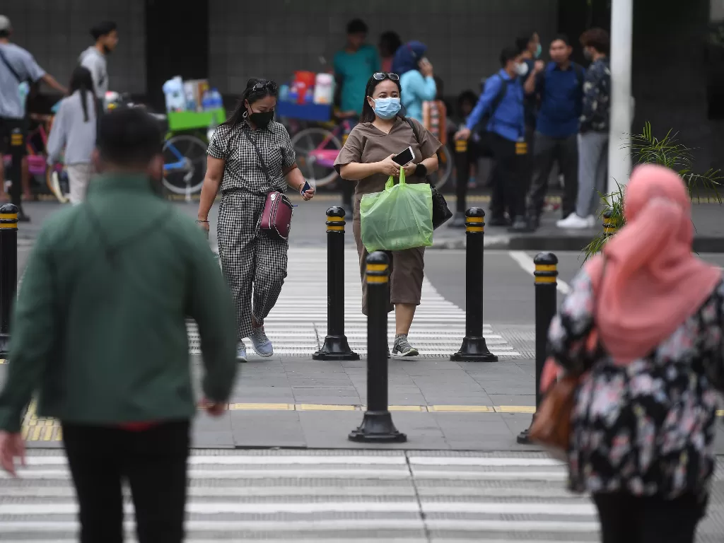 Warga mengenakan masker saat melintas di Jalan MH Thamrin, Jakarta, Rabu (12/1/2022). (ANTARA/Akbar Nugroho Gumay)