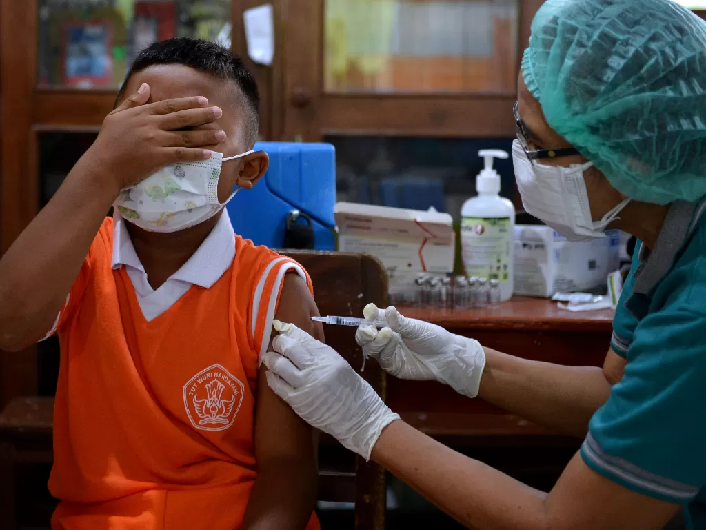 Vaksinator menyuntikkan vaksin COVID-19 kepada pelajar SD Negeri 28 Dangin Puri saat pelaksanaan vaksinasi COVID-19 untuk anak 6-11 tahun di Denpasar, Bali, Sabtu (22/1/2022). (ANTARA FOTO/Fikri Yusuf)