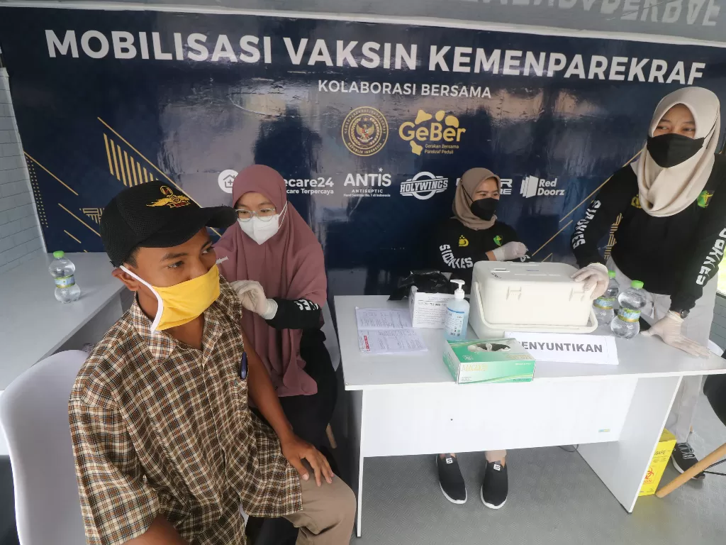 Petugas kesehatan menyuntikkan vaksin COVID-19 di atas mobil Vaksinasi Keliling milik Kementerian Pariwisata dan Ekonomi Kreatif (Kemenparekraf) di kawasan wisata Simpang Lima Gumul, Kediri, Jawa Timur, Minggu (19/12/2021). (ANTARA/Prasetia Fauzani)