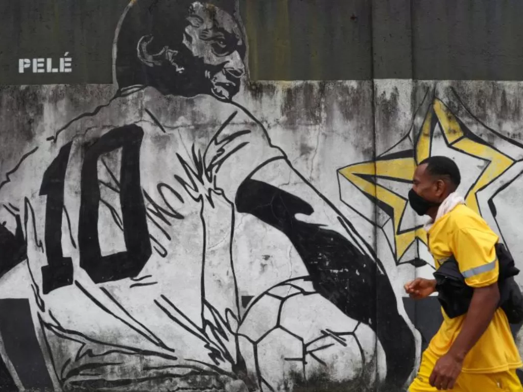 Seorang pria berjalan melewati mural mirip legenda sepak bola Brazil, Pele, di Santos, Brazil, Rabu (27/10/2021). (ANTARA FOTO/REUTERS/Amanda Perobelli/WSJ/cfo)