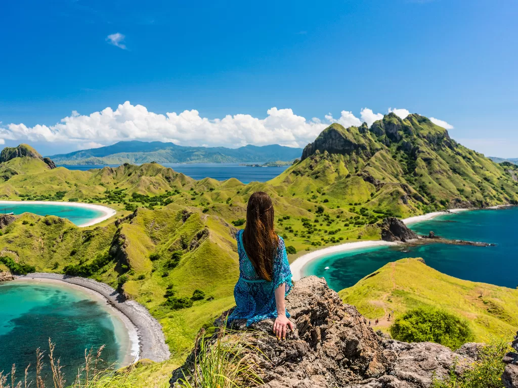Seorang wisatawan duduk menatap danau di Pulau Padar, Labuan Bajo. (Shutterstock/Kzenon)
