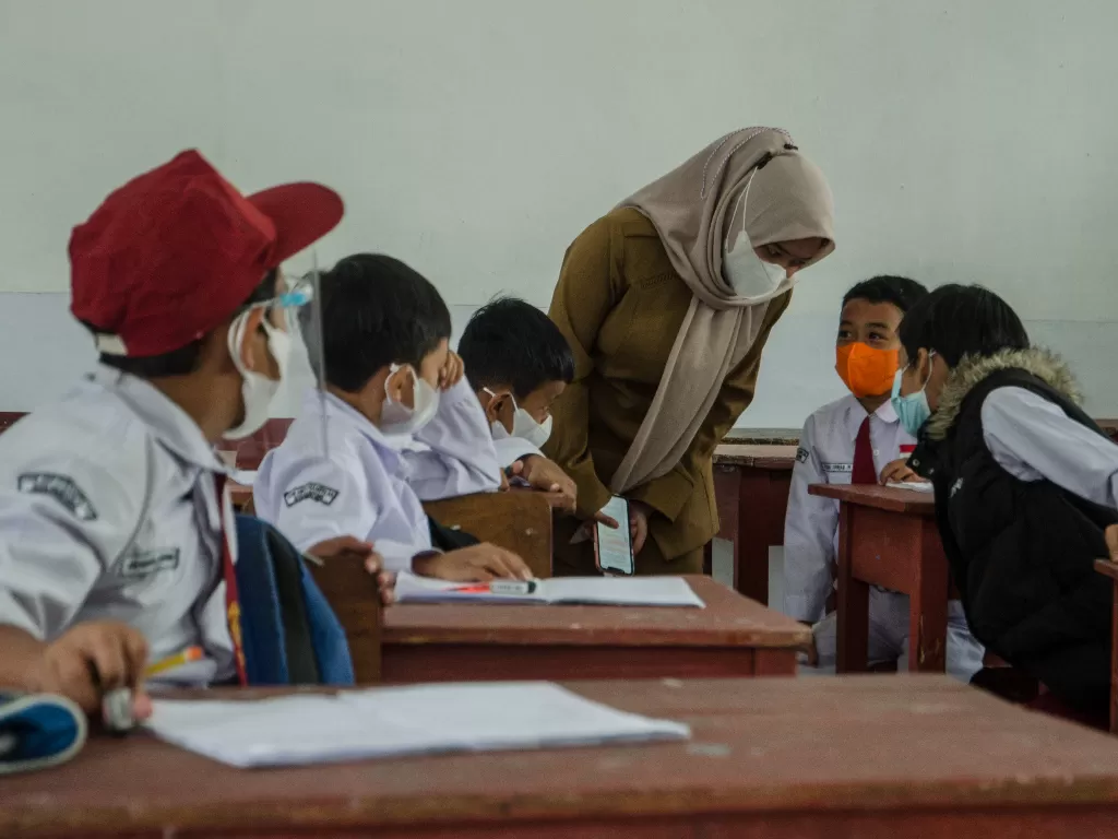 Guru mengajarkan murid pada pelaksanaan pembelajaran tatap muka (PTM) 100 persen di SDN 065 Cihampelas, Bandung, Jawa Barat. (ANTARA FOTO/Novrian Arbi)