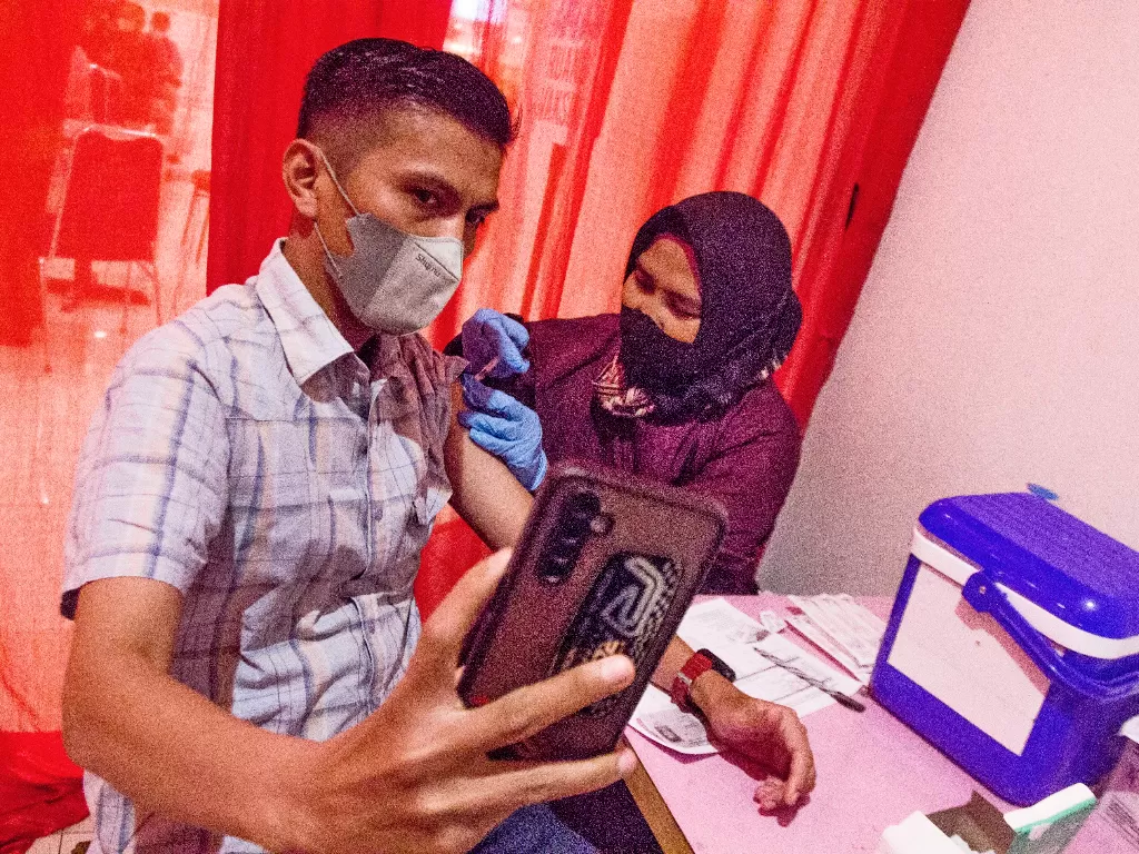 Vaksinator menyuntikkan vaksin COVID-19 saat pelaksanaan vaksinasi malam hari di kawasan Galuh Mas, Karawang, Jawa Barat, Senin (7/2/2022). (ANTARA/M Ibnu Chazar)