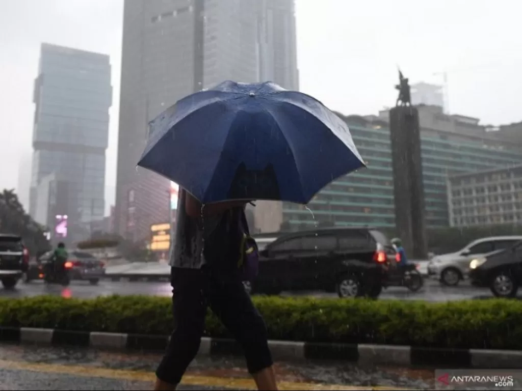 Warga menggunakan payung untuk menghindari hujan saat melewati kawasan Bundaran Hotel Indonesia, Jakarta. (ANTARA FOTO/Akbar Nugroho Gumay)