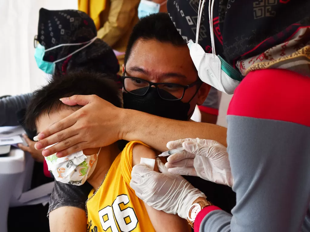 Petugas kesehatan menyuntikkan vaksin COVID-19 kepada seorang anak saat digelar Vaksinasi COVID-19 massal di ruang publik kawasan Sumber Wangi, Kota Madiun, Jawa Timur, Senin (14/2/2022). (ANTARA/Siswowidodo)