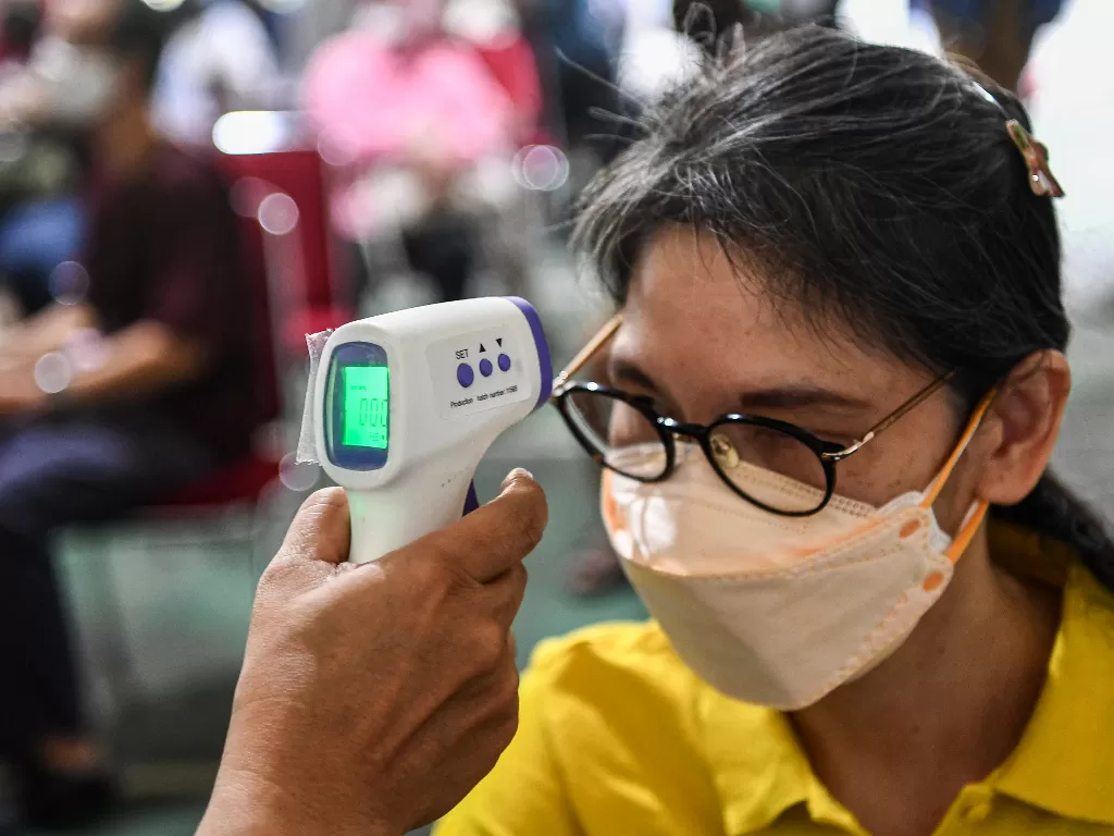 Tenaga kesehatan memeriksa suhu tubuh dari warga sebelum mendapatkan vaksin COVID-19 di sentra vaksinasi COVID-19 oleh Prudential di RPTRA Taman Mandala, Tebet, Jakarta, Senin (21/2/2022). (ANTARA FOTO/M Risyal Hidayat)