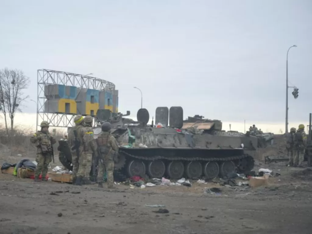 Prajurit Ukraina berjaga di samping kendaraan lapis baja yang hancur di pinggiran Kharkiv, Ukraina. (REUTERS/Maksim Levin)
