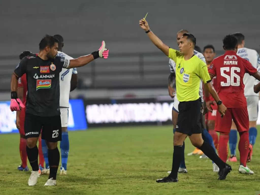 Wasit Fariq Hitaba (ketiga kanan) memberikan kartu kuning kepada penjaga gawang Persija Jakarta Andritany (kiri) setelah terlibat keributan dengan pemain Persib Bandung dalam pertandingan sepak bola Liga 1 di Stadion I Wayan Dipta, Gianyar, Bali, Selasa (
