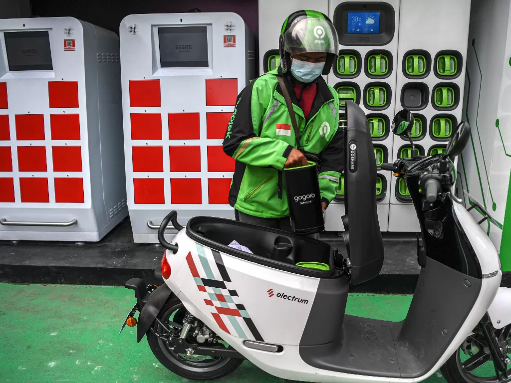 Seorang pengemudi ojek daring mengganti baterai sepeda motor listrik dengan yang sudah penuh terisi di Stasiun Penukaran Baterai Kendaraan Listrik Umum (SPBKLU) di SPBU Pertamina, Jalan MT Haryono, Jakarta. (ANTARA/M Risyal Hidayat)