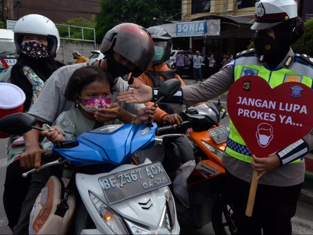 Anggota Satlantas Polda Lampung memberikan edukasi keselamatan berkendara dan prokes kepada pengendara. (ANTARA FOTO/Ardiansyah)