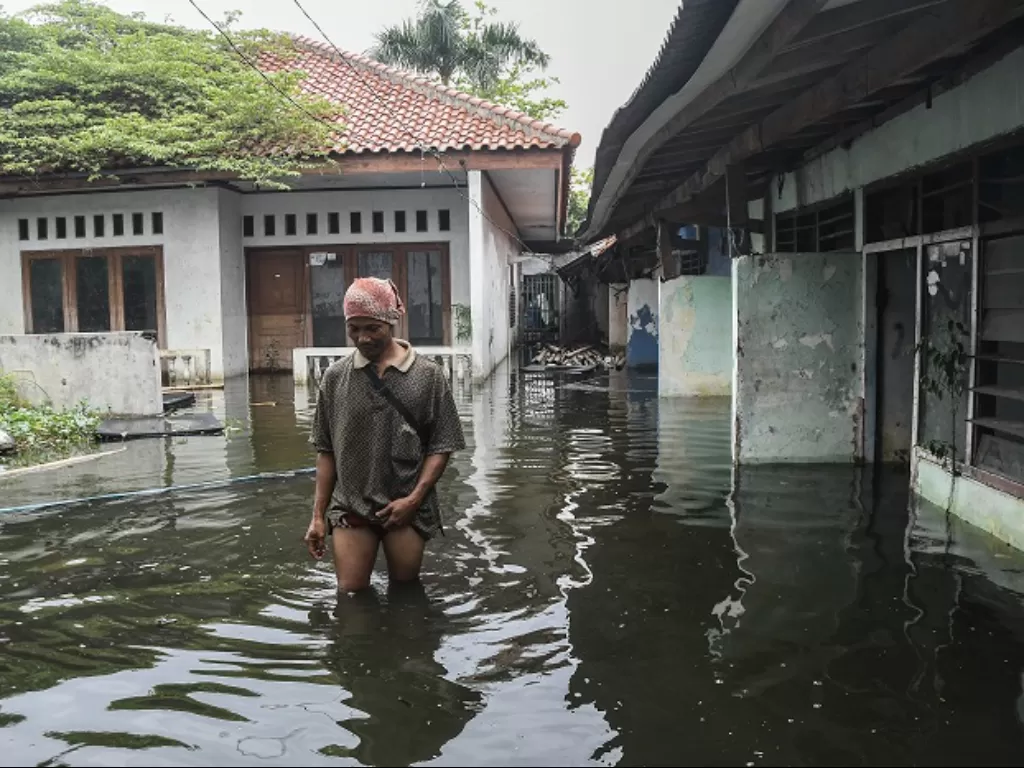 Seorang warga melintasi banjir di Duren Sawit, Jakarta Timur. (ANTARA FOTO/Fakhri Hermansyah)