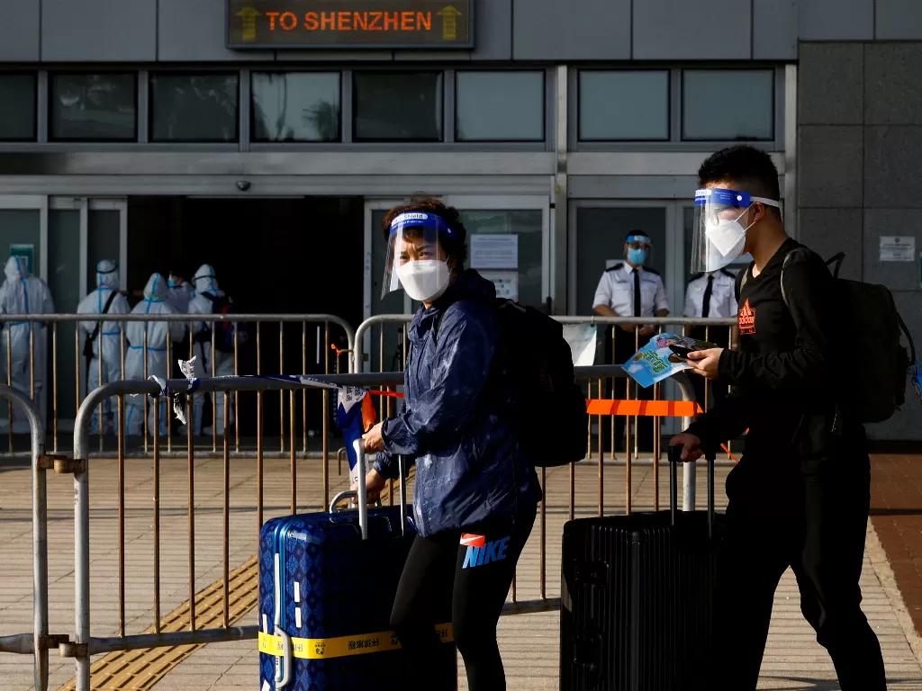 Pelancong mengenakan masker dan pelindung wajah, berjalan di perbatasan China-Hong Kong di Pelabuhan Teluk Shenzhen, selama pandemi penyakit coronavirus (COVID-19) di Hong Kong. (REUTERS/REUTERS/Tyrone Siu)