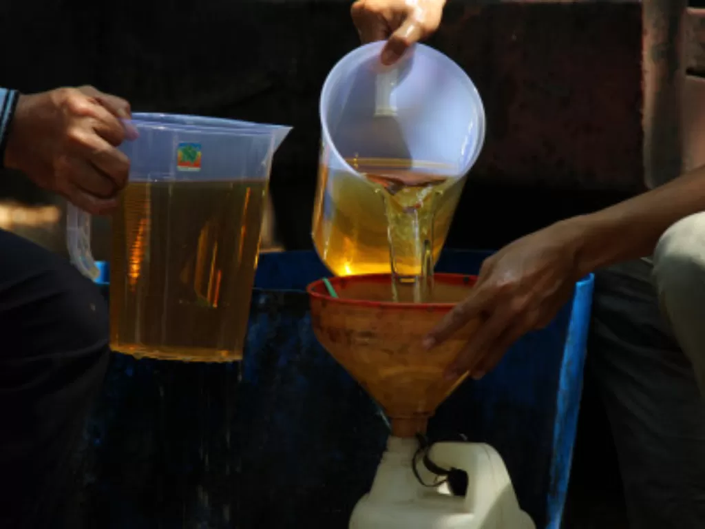 Dua pekerja menuangkan minyak goreng ke wadah milik warga saat giat pasar murah minyak goreng curah di kawasan Jalan Ujungpandang, Pontianak, Kalimantan Barat (Ilustrasi/ANTARA FOTO/Jessica Helena Wuysang)