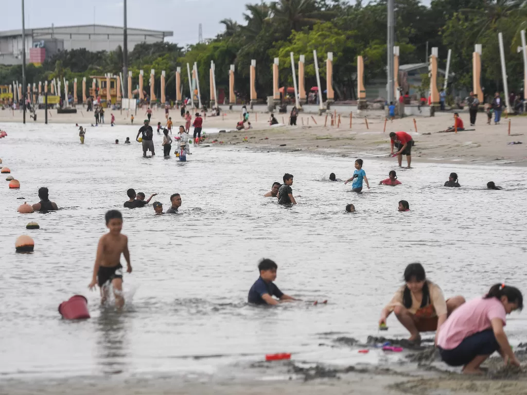 Sejumlah warga bermain di area pantai Taman Impian Jaya Ancol, Jakarta, Minggu (3/4/2022). (ANTARA/Hafidz Mubarak)