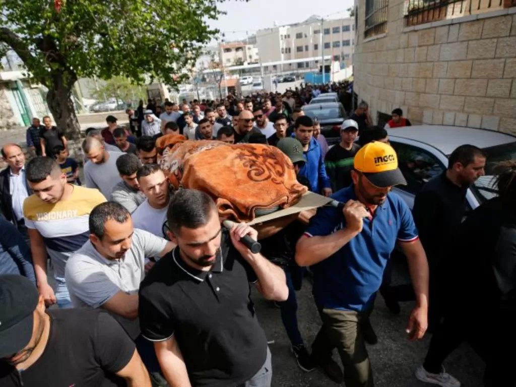 Warga Palestina membawa jenazah wanita yang ditembak pasukan Israel. (REUTERS/Mussa Qawasma)