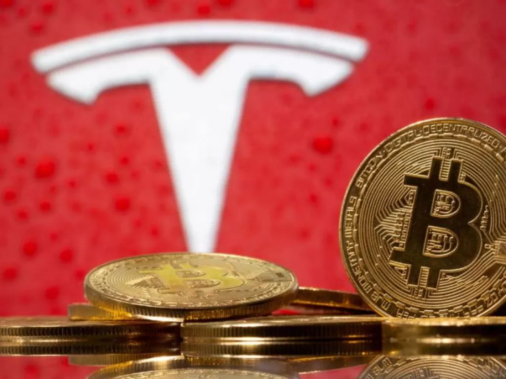 Representasi mata uang virtual Bitcon terlihat di depan logo Tesla. Ilustrasi diambil 9 Februari 2021. (ANTARA/Reuters/Dado Ruvic)