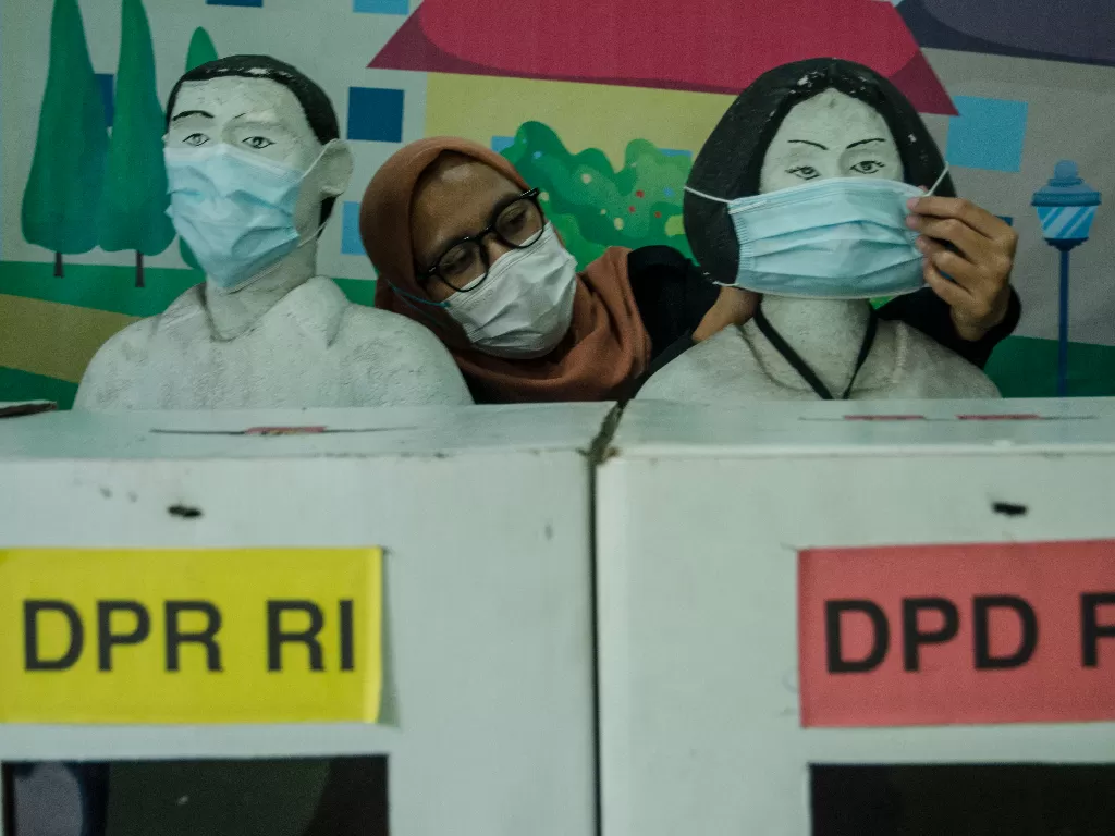 Petugas merapikan masker yang dipasang pada diorama suasana pemungutan suara di TPS saat Pemilu di Kantor KPU Jawa Barat, Bandung, Jawa Barat. (ANTARA/Novrian Arbi)