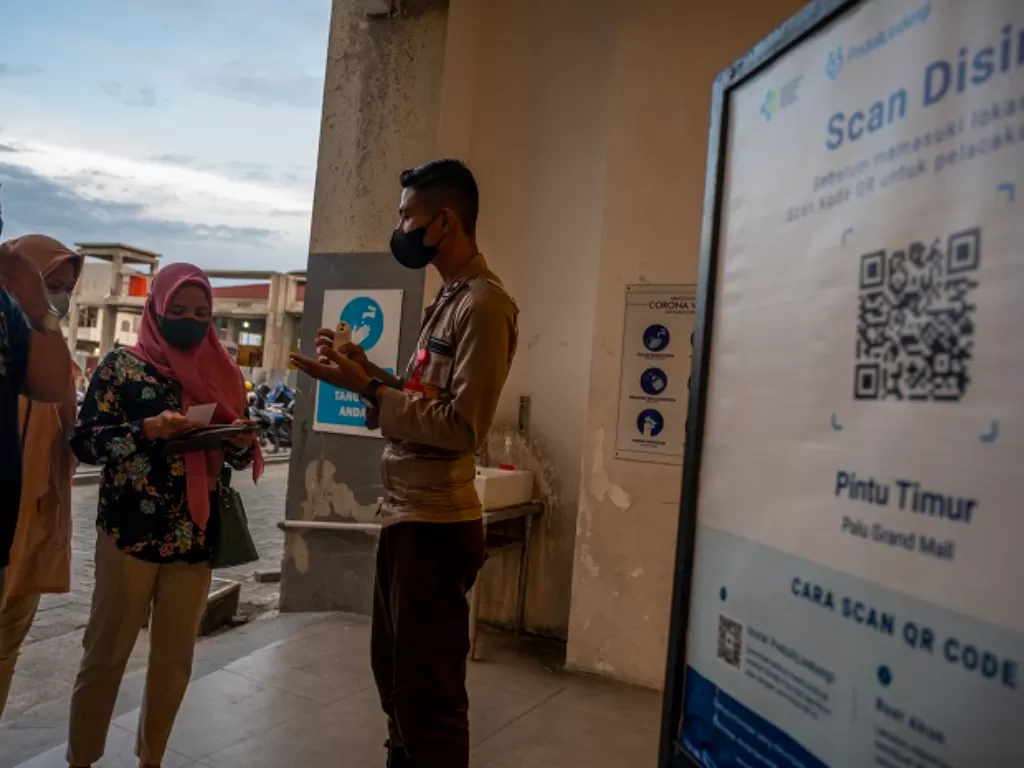 Petugas meminta warga melakukan pemindaian kode batang melalui aplikasi PeduliLindungi sebelum masuk di sebuah pusat perbelanjaan. (ANTARA FOTO/Basri Marzuki)