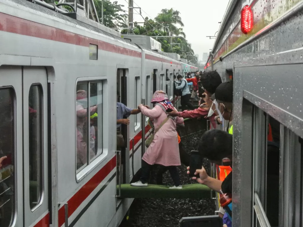 Petugas membantu penumpang KRL Commuterline berpindah rangkaian kereta. (ANTARA/Paramayuda)