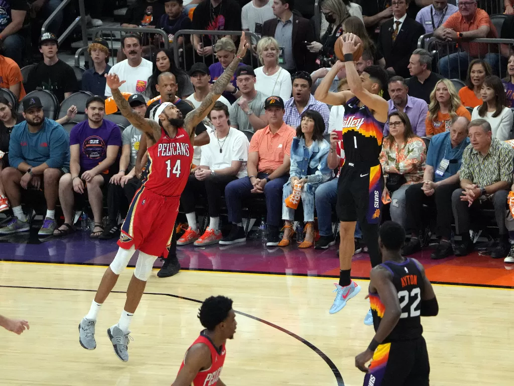 Guard Phoenix Suns Devin Booker (1) menembak pemain depan New Orleans Pelicans Brandon Ingram (14) pada paruh pertama pertandingan babak pertama playoff NBA 2022 di Footprint Center. (REUTERS)