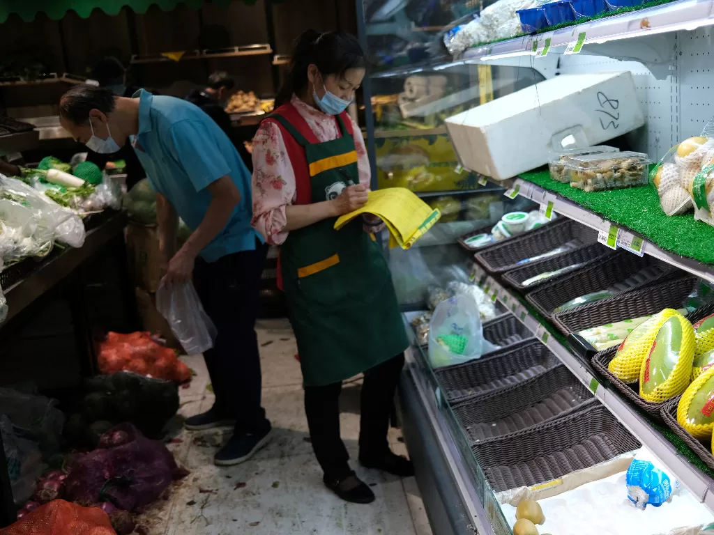 Seorang anggota staf mencatat barang-barang di lemari es setengah kosong untuk buah-buahan, menyusul terjadi panic buying yang terjadi di Beijing, China. (REUTERS/Tingshu Wang)