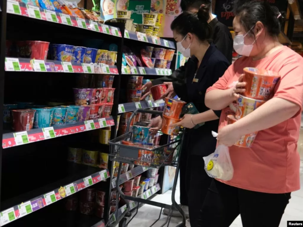 Warga Beijing, China berbelanja makanan instan di sebuah supermarket, di antara rak-rak makanan yang mulai kosong akibat diserbu warga yang menimbun makanan dan kebutuhan harian lainnya. (Reuters)