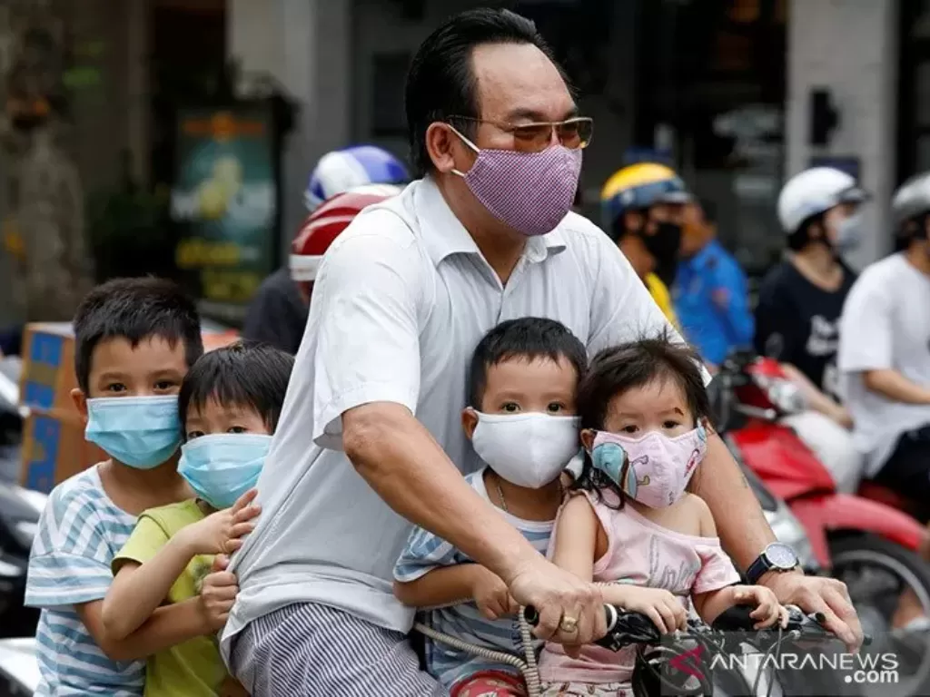 Seorang pria mengendarai sepeda membawa anak-anaknya melewati sebuah jalan ditengah mewabahnya virus corona (COVID-19), di Hanoi, Vietnam, Senin (27/7/2020). (REUTERS/Kham via Antara)