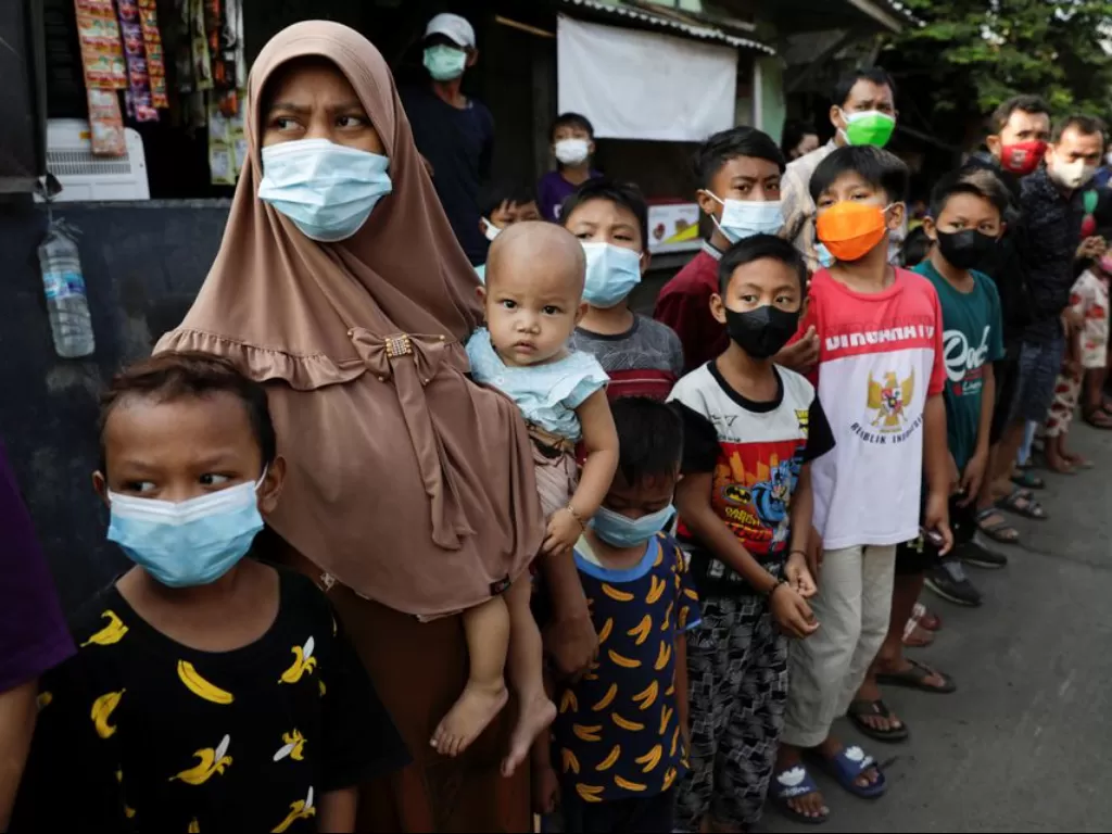 Warga mengenakan masker untuk mencegah penyebaran COVID-19, mengantre untuk menerima bantuan dari presiden Indonesia di Jakarta, Indonesia, 16 Juli 2021. (REUTERS/Willy Kurniawan)