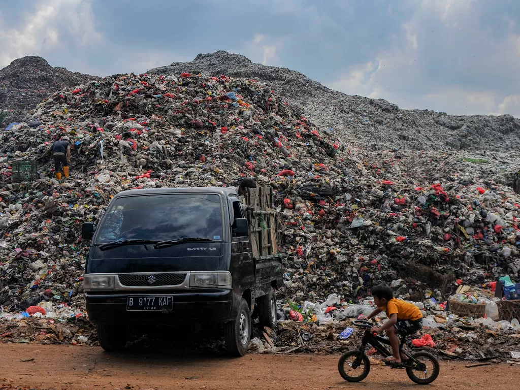 Seorang anak bersepeda melintasi tumpukan sampah di TPA (Tempat Pembuangan Akhir) Burangkeng, Setu, Kabupaten Bekasi, Jawa Barat, Rabu (8/6/2022). (ANTARA/Fakhri Hermansyah)
