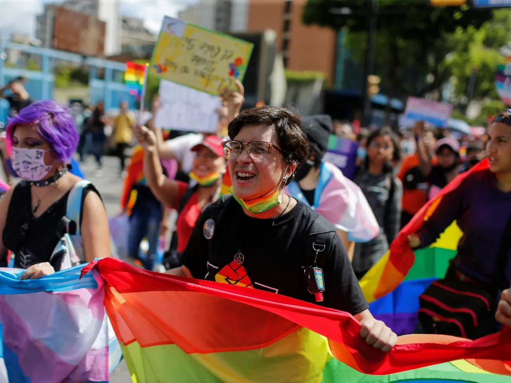 Seorang transgender memegang bendera pelangi dalam pawai untuk menandai Hari Internasional Melawan Homofobia, Transfobia, dan Bifobia, yang diperingati pada 17 Mei, di Caracas, Venezuela, 28 Mei 2022. (REUTERS/Leonardo Fernandez Viloria)