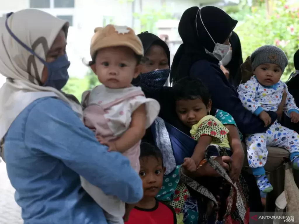 Warga membawa anak mereka untuk mendapatkan imunisasi di posyandu di Kota Banda Aceh, Provinsi Aceh, Kamis (8/7/2021. Kegiatan posyandu antara lain mencakup pelayanan kesehatan bagi ibu dan anak serta penyuluhan gizi untuk mencegah kasus stunting. (ANTARA