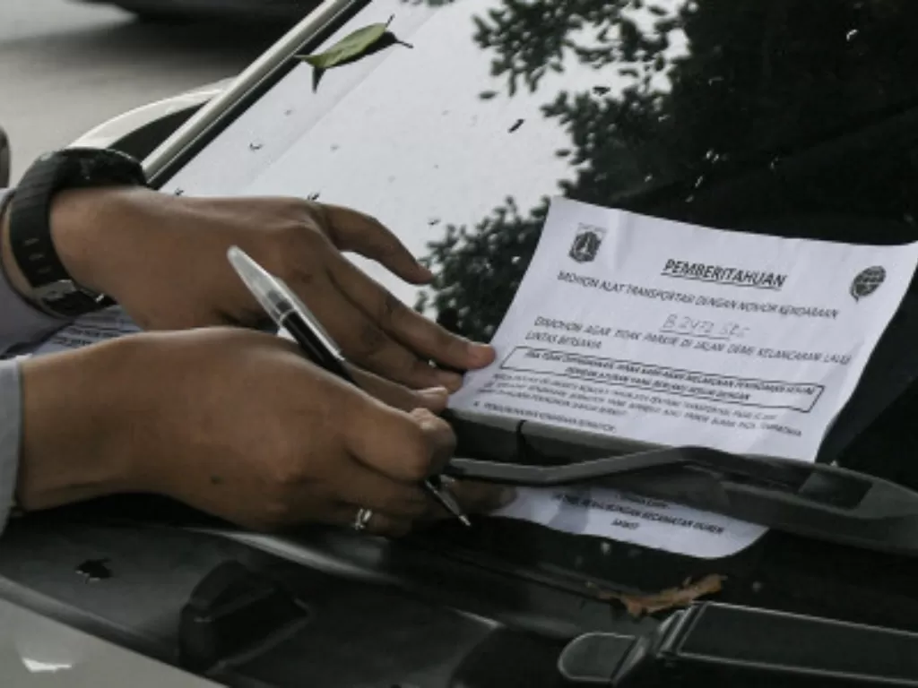 Iustrasi Petugas Dinas Perhubungan menempelkan surat peringatan di atas mobil yang parkir di trotoar kota Jakarta. (ANTARA FOTO/ Fakhri Hermansyah)