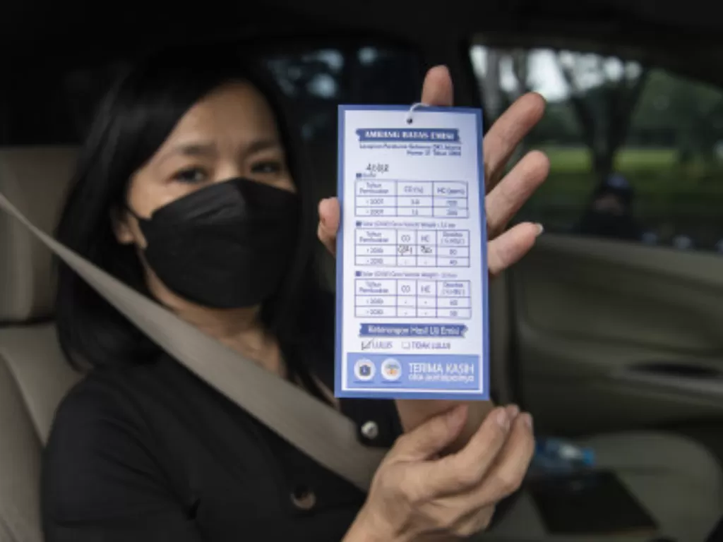 Pengendara mobil menunjukkan kartu hasil uji emisi kendaraannya di Jalan Benyamin Sueb, Pademangan, Jakarta Utara. (ANTARA FOTO/Sigid Kurniawan)
