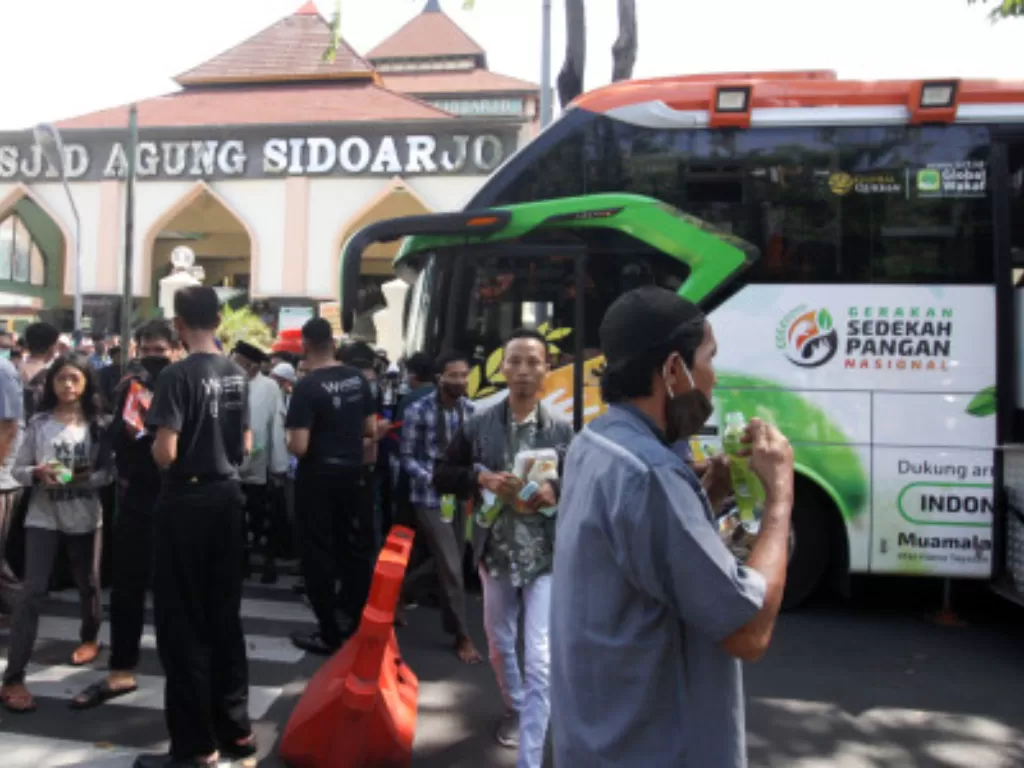 Warga menerima makanan dan minuman secara gratis dari Armada Humanity Food Bus Aksi Cepat Tanggap (ACT) di kawasan Masjid Agung Sidoarjo, Jawa Timur. (ANTARA FOTO/Umarul Faruq)