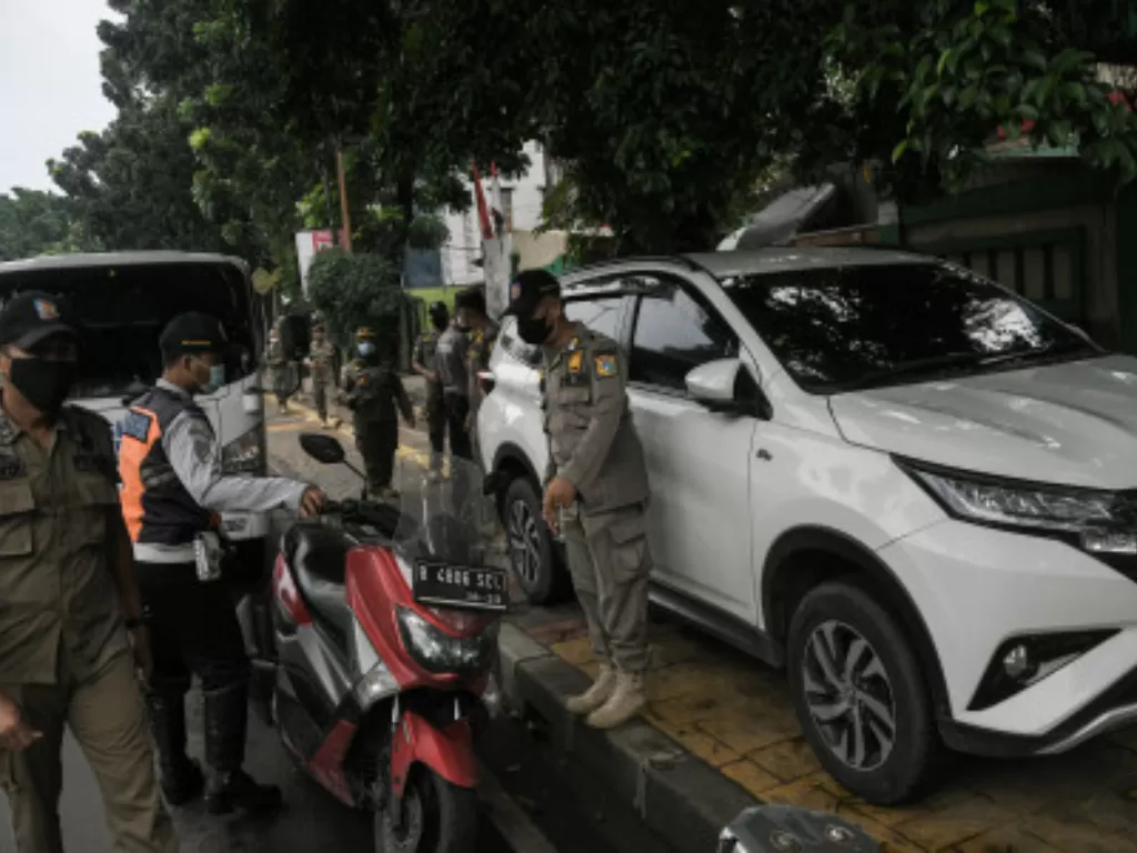 Sejumlah petugas gabungan dari Dinas Perhubungan dan Satpol PP menertibkan mobil dan motor yang parkir liar di trotoar kawasan Duren Sawit, Jakarta Timur. (ANTARA FOTO/ Fakhri Hermansyah)